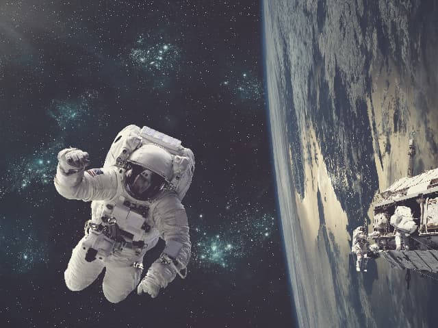 Astronaut floating in space in front of earth near satellite
