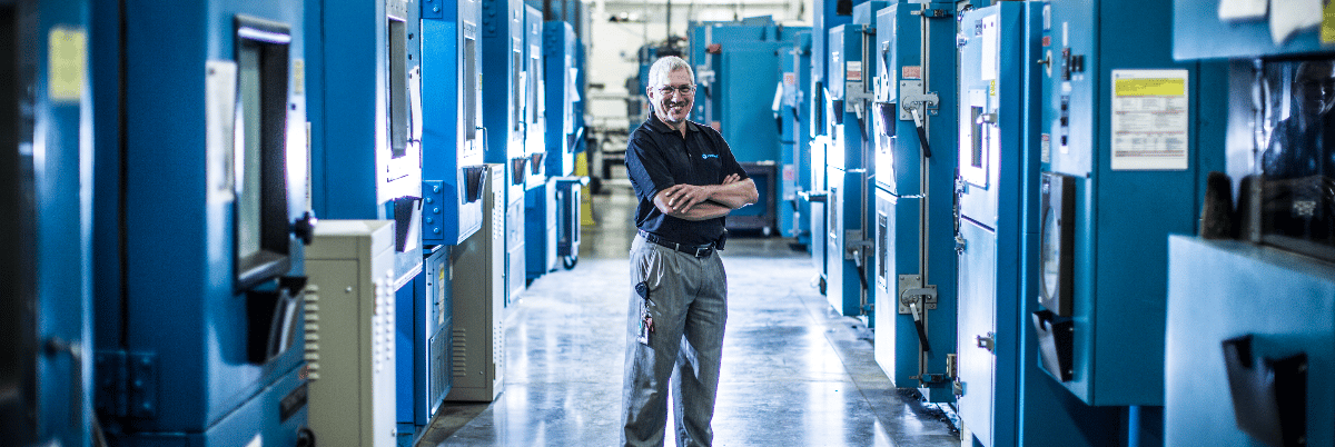 Element testing specialist standing among environmental test chambers in product testing lab